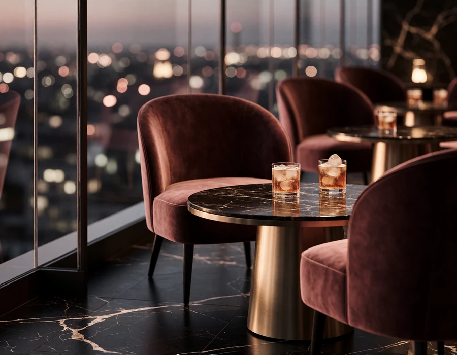 Velvet armchairs and a marble table with cocktails beside floor-to-ceiling glass overlooking the Houston skyline